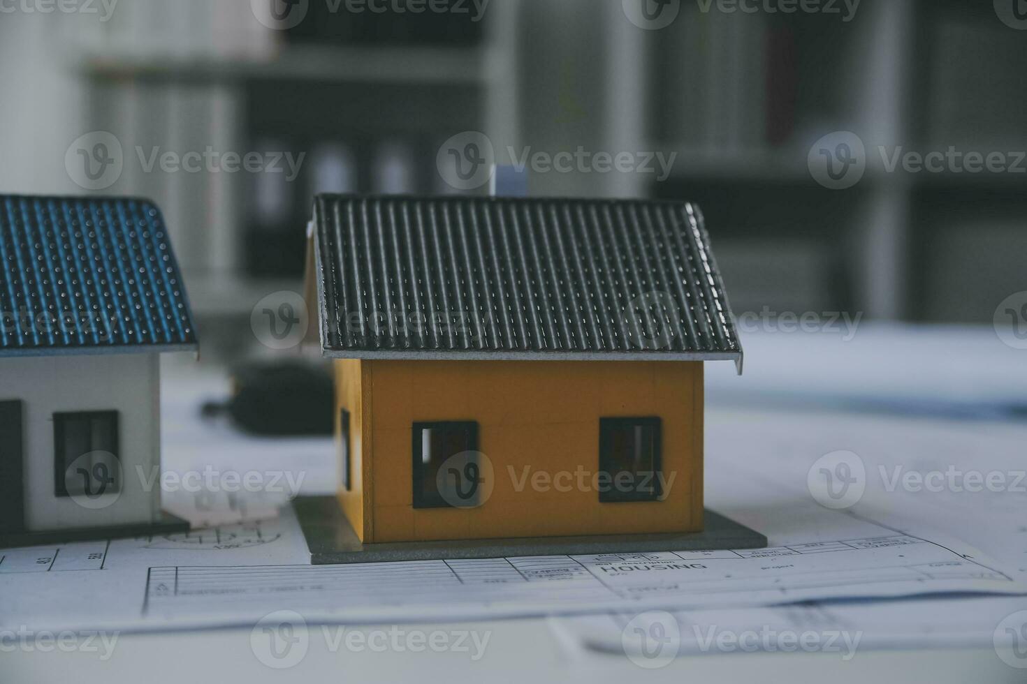 architectural model of houses on desk with drawing technical tools and blueprint rolls, isolated on white background, for building construction plan, interior designer and architect work concept photo