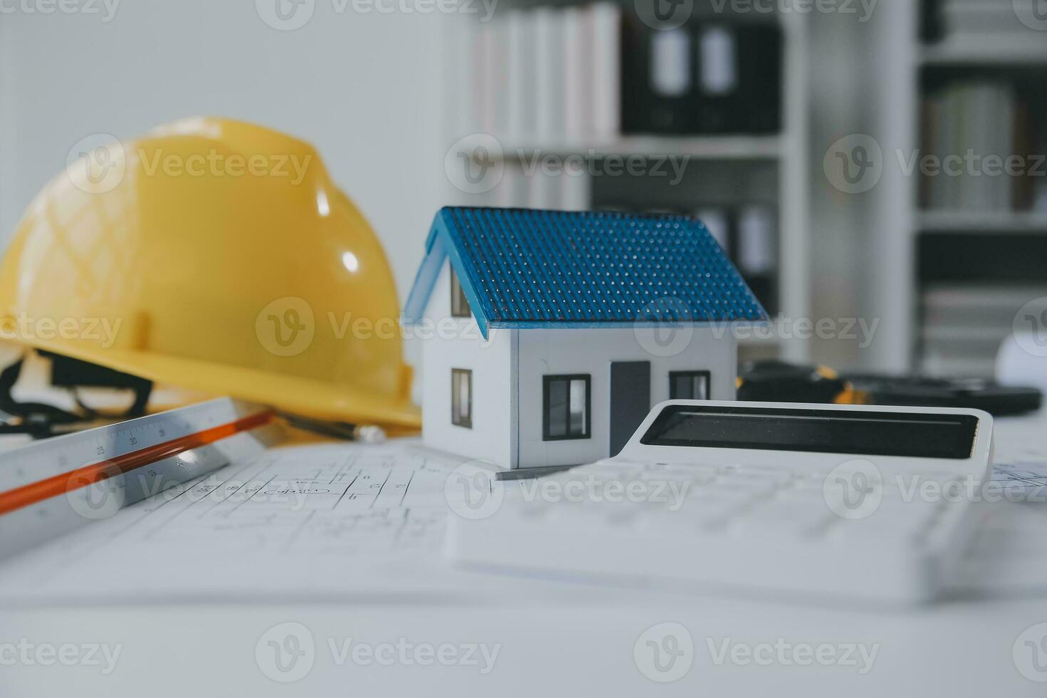 architectural model of houses on desk with drawing technical tools and blueprint rolls, isolated on white background, for building construction plan, interior designer and architect work concept photo