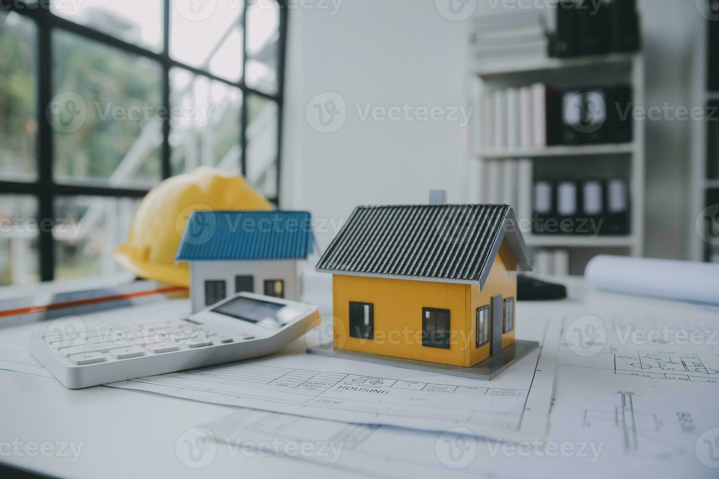 architectural model of houses on desk with drawing technical tools and blueprint rolls, isolated on white background, for building construction plan, interior designer and architect work concept photo