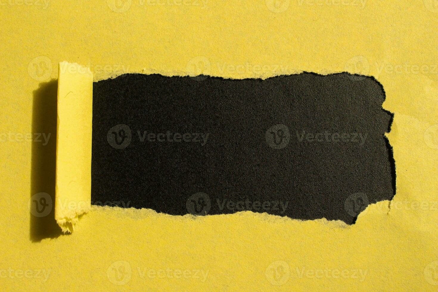 Yellow torn paper hole on a black background with copy space for your text photo