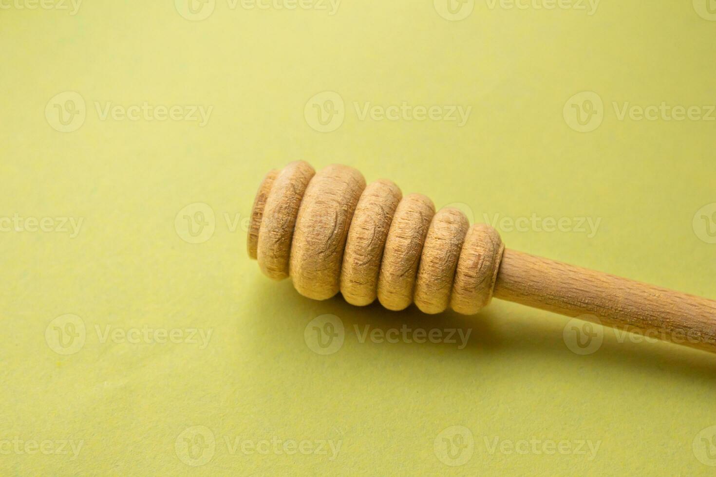 Wooden honey dipper isolated on a yellow background. Copy space for text. photo