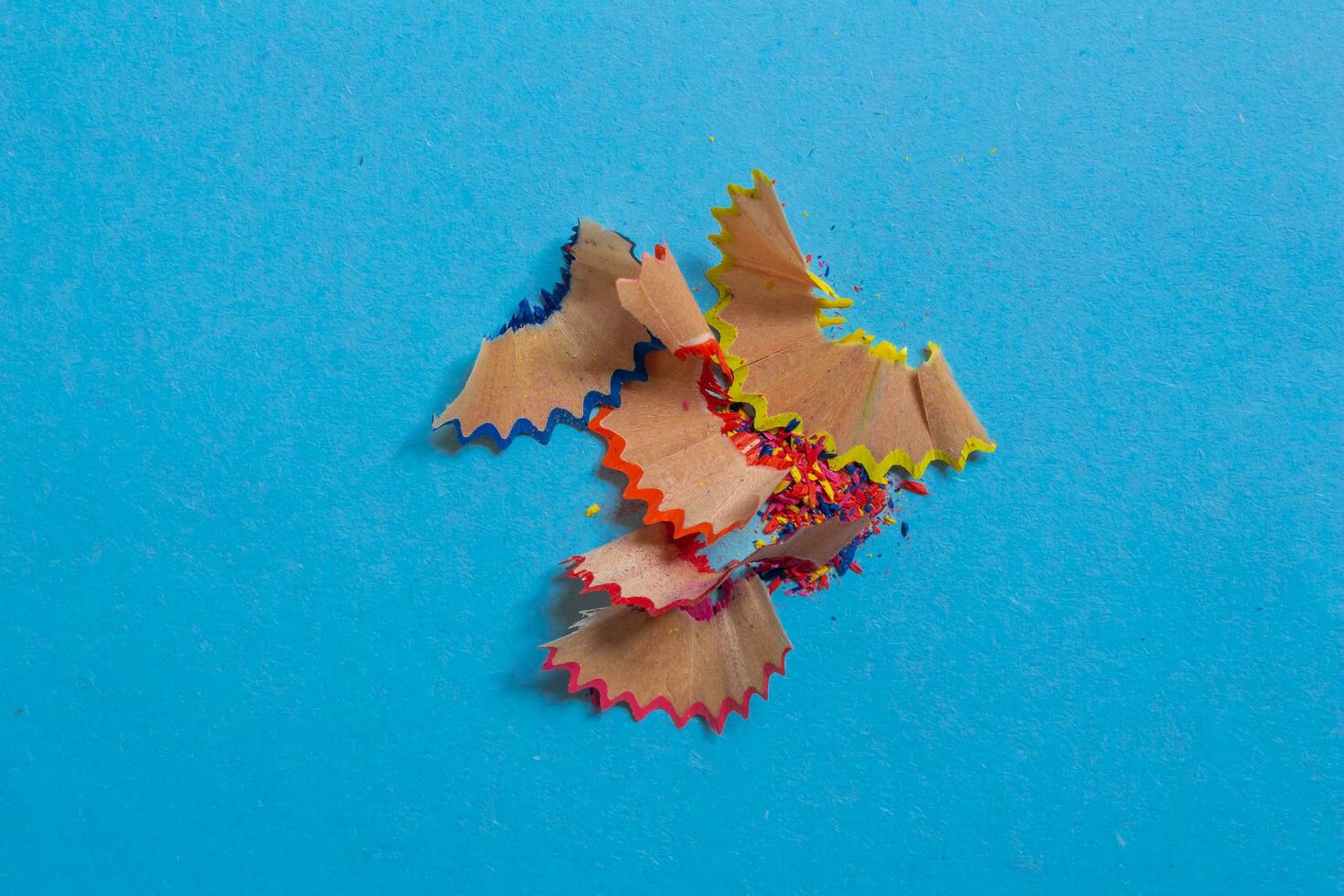 Pencil shavings isolated on a blue background. Top view, flat lay. photo