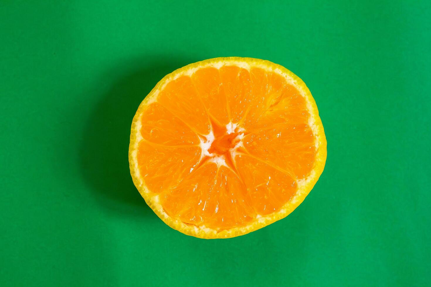 Sliced tangerine isolated on a green background. Top view. photo