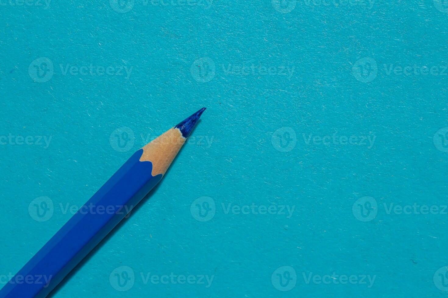 Blue crayon pencil isolated on a blue background. Top view, copy space. photo