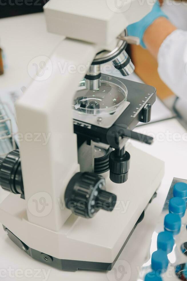 científico o médico en laboratorio Saco trabajando en biotecnológico laboratorio, microscopio equipo para investigación con mezcla reactivos en vaso matraz en clínico laboratorio. foto