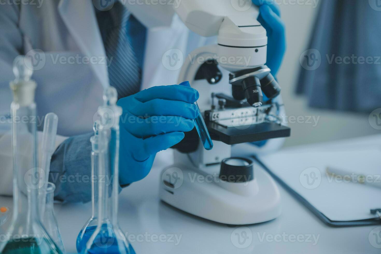 biochemical research scientist team working with microscope for coronavirus vaccine development in pharmaceutical research labolatory, selective focus photo