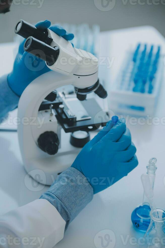 biochemical research scientist team working with microscope for coronavirus vaccine development in pharmaceutical research labolatory, selective focus photo