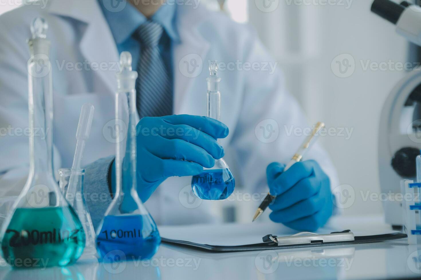 biochemical research scientist team working with microscope for coronavirus vaccine development in pharmaceutical research labolatory, selective focus photo