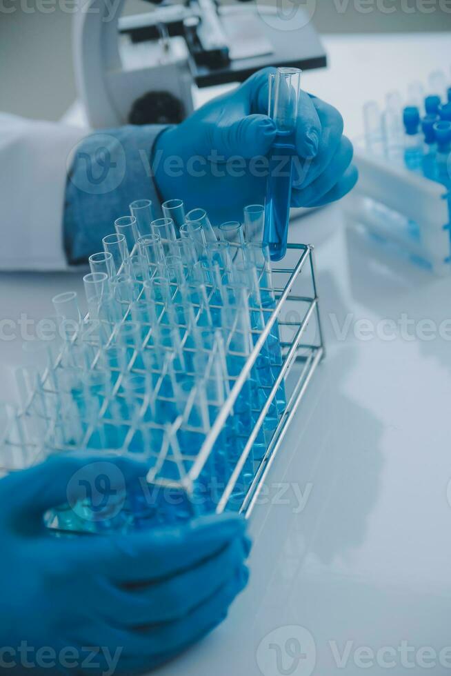 biochemical research scientist team working with microscope for coronavirus vaccine development in pharmaceutical research labolatory, selective focus photo