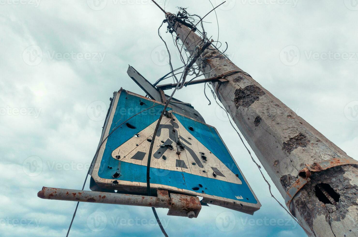 concrete pillar broken by shards and a road sign against a gloomy sky photo