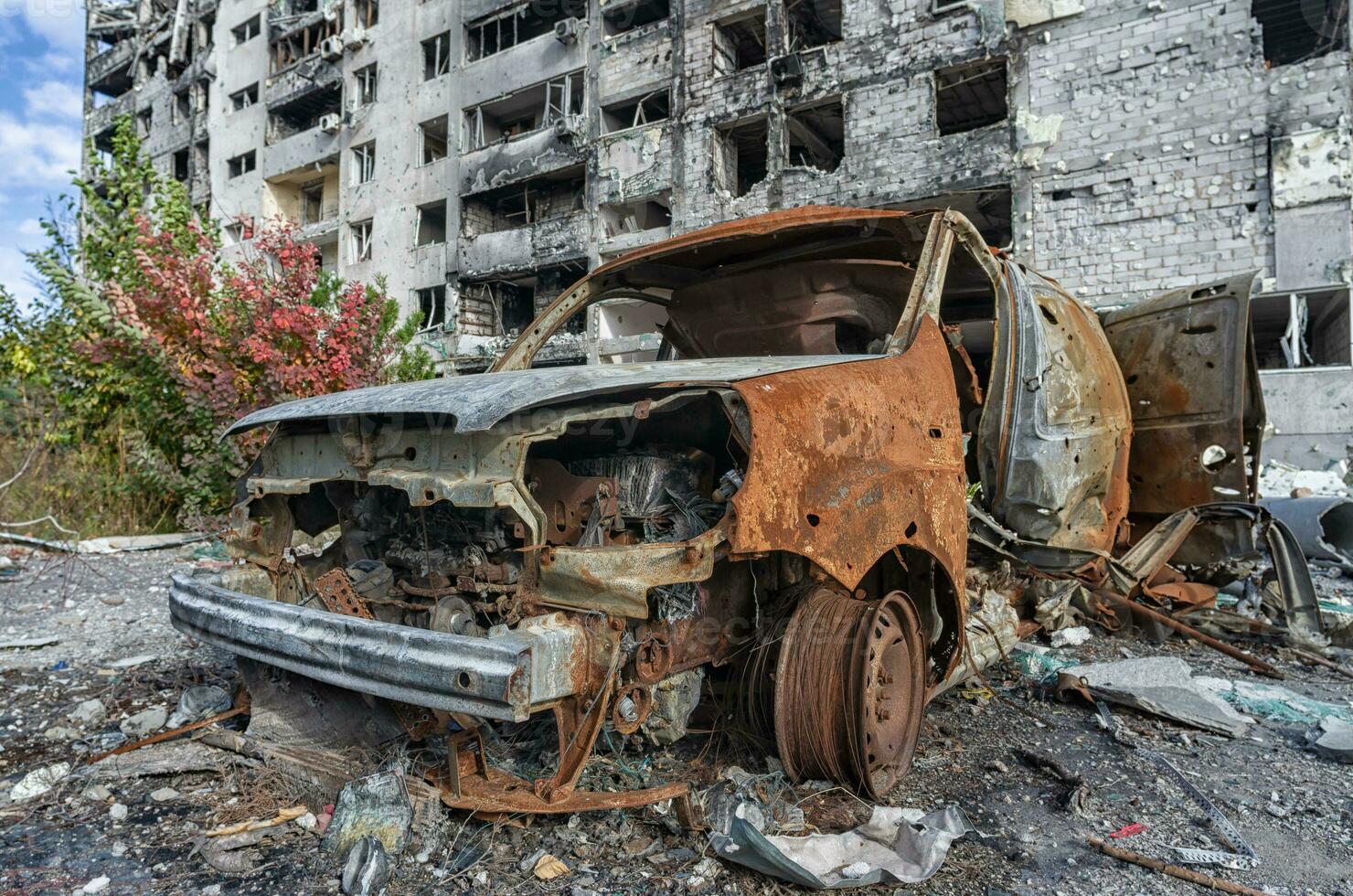 quemado estropeado arriba coche en contra el antecedentes de un destruido casa en Ucrania foto