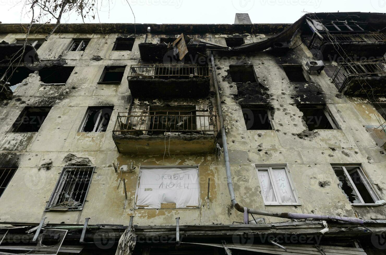 inscription in Russian letters people live here in the window of a burnt and shot house in Ukraine photo
