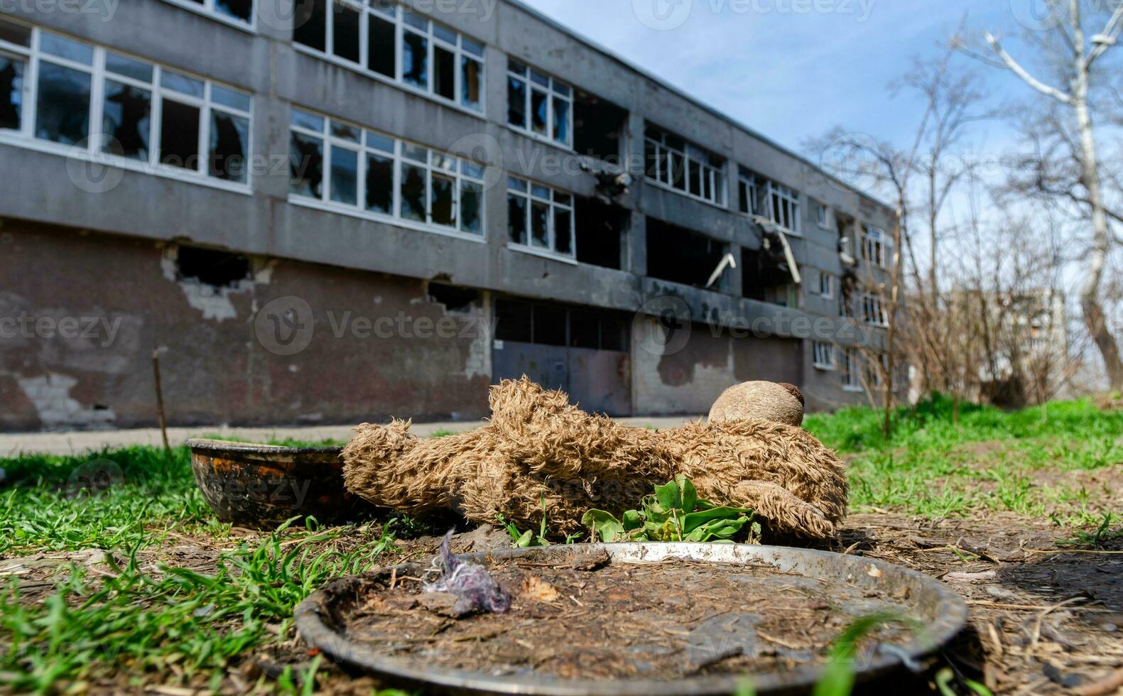 dirty toys on the background of a burned-out destroyed school in an abandoned city in Ukraine photo