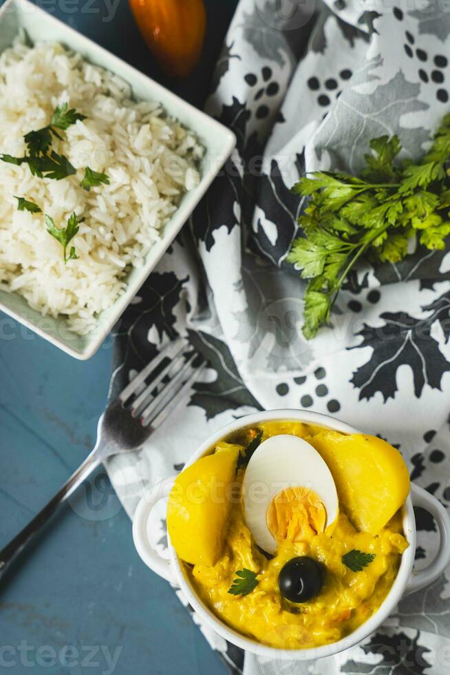Typical Peruvian dish called Aji de gallina with a portion of rice on a blue background. photo