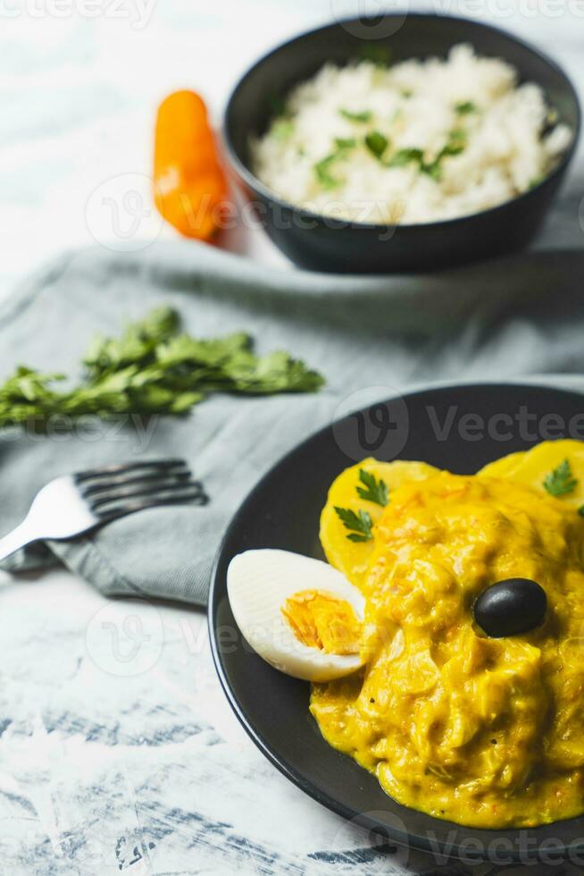 Typical Peruvian dish called Aji de gallina with a portion of rice on a light background. photo