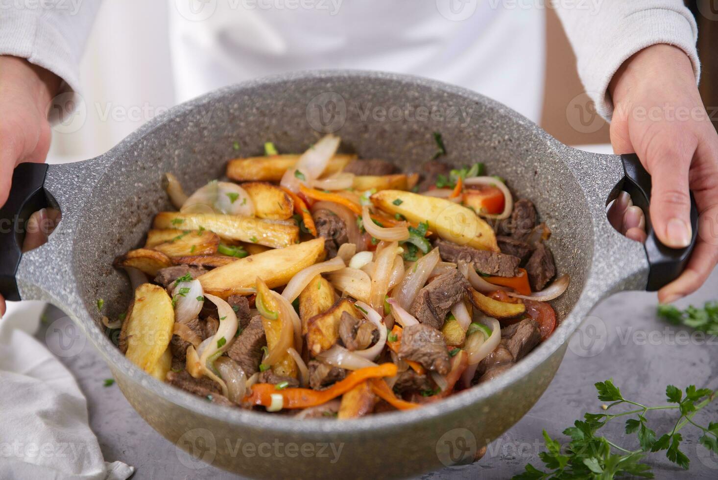 manos participación cazuela con un típico peruano plato llamado lomo saltado. foto