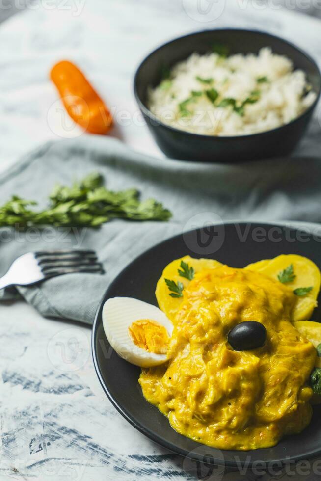 Typical Peruvian dish called Aji de gallina with a portion of rice on a light background. photo