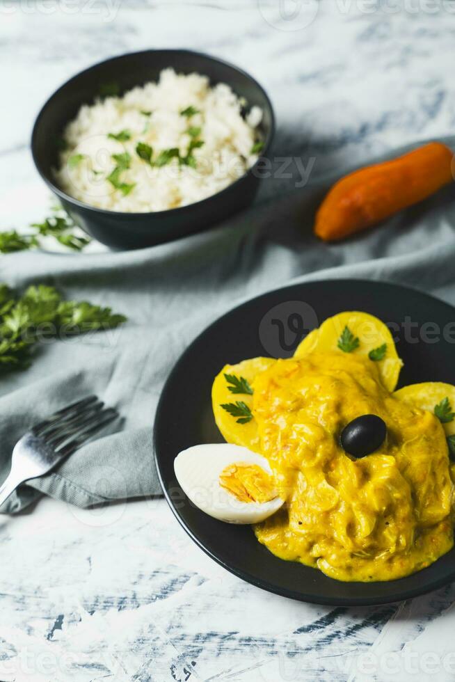 Typical Peruvian dish called Aji de gallina with a portion of rice on a light background. photo
