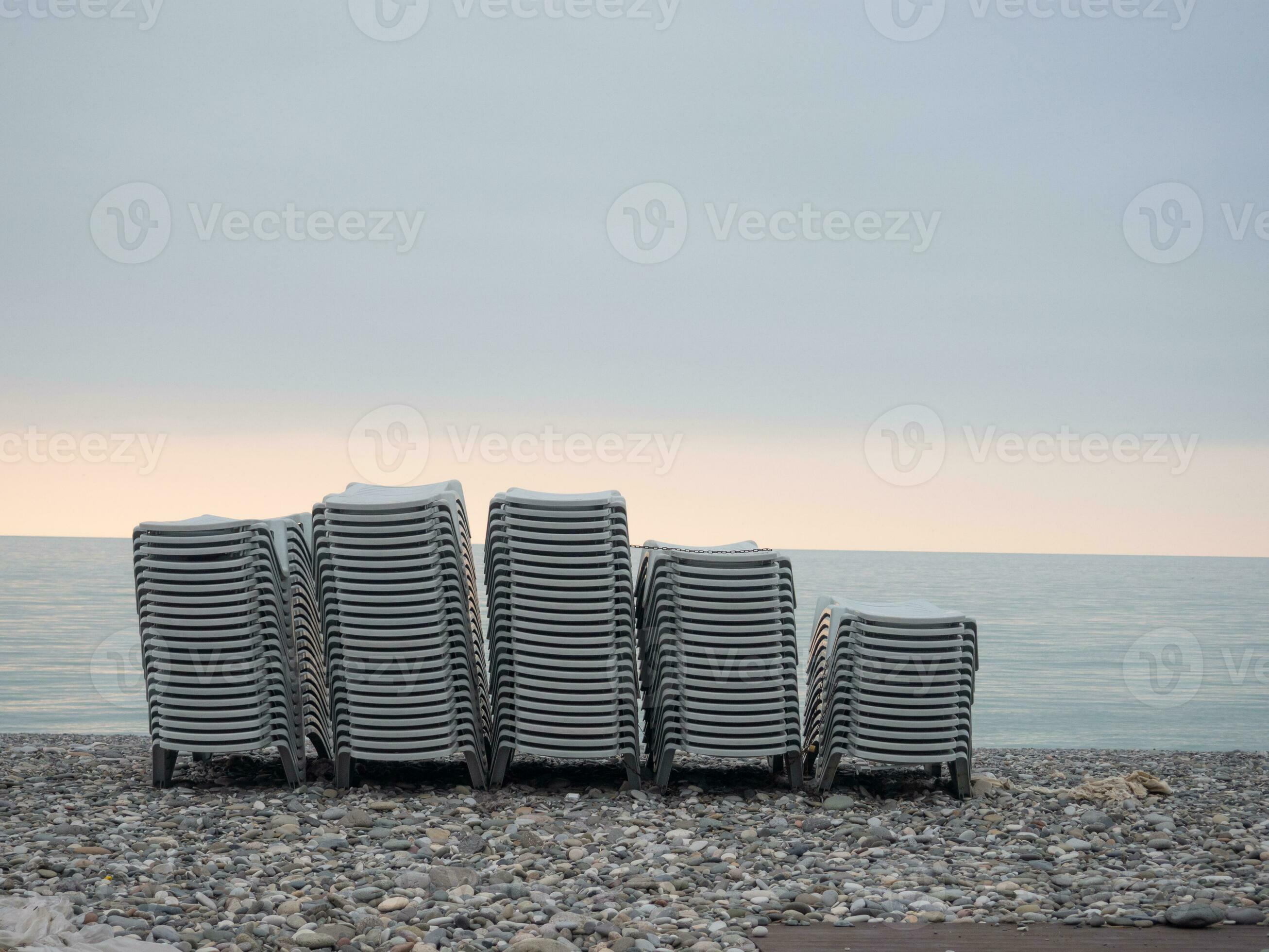 Stacked plastic sun loungers on the beach. Sunbeds in bad weather. Resort in off season