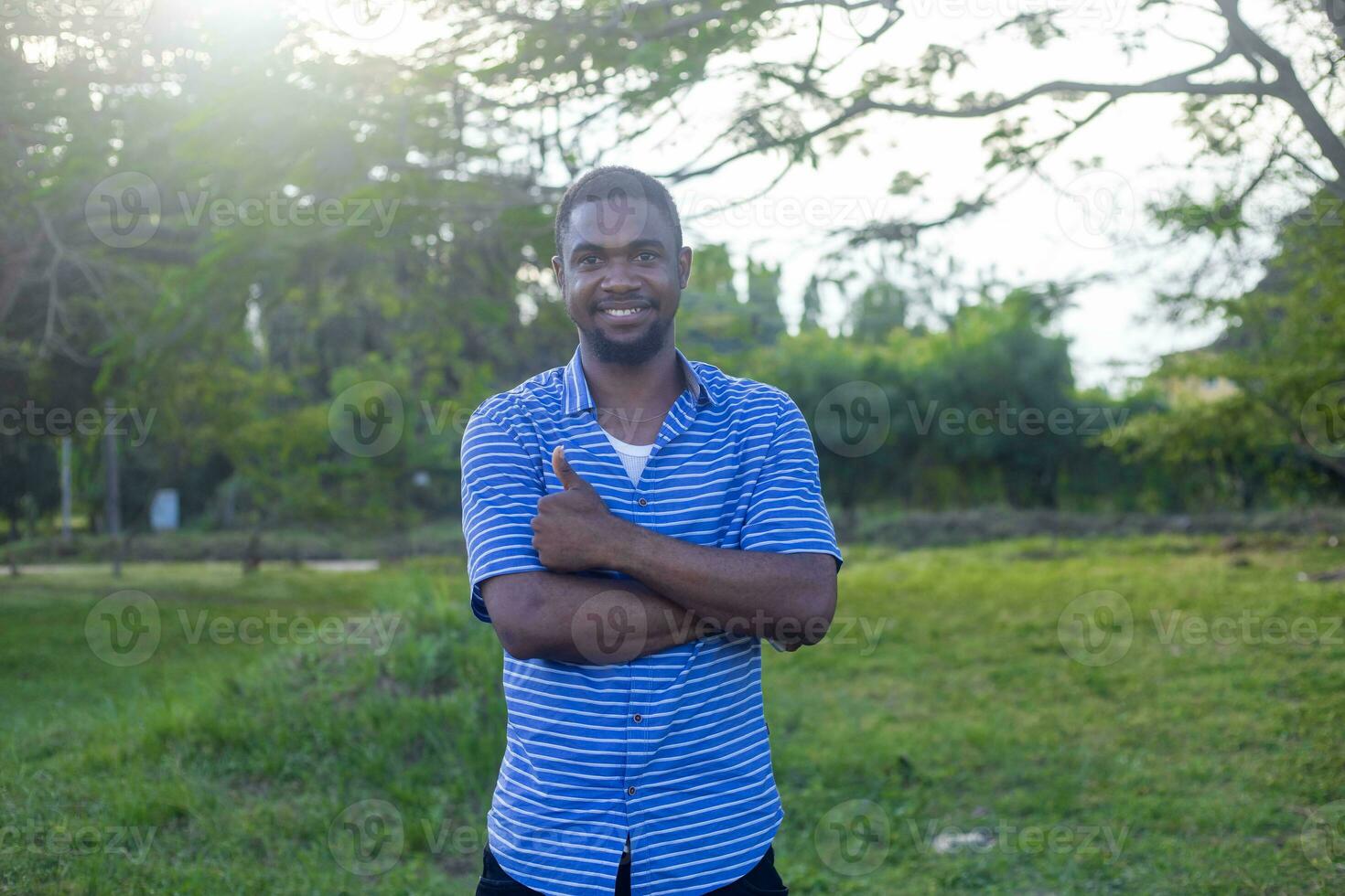 Portrait of a happy young man posing with arms crossed or hands folded photo