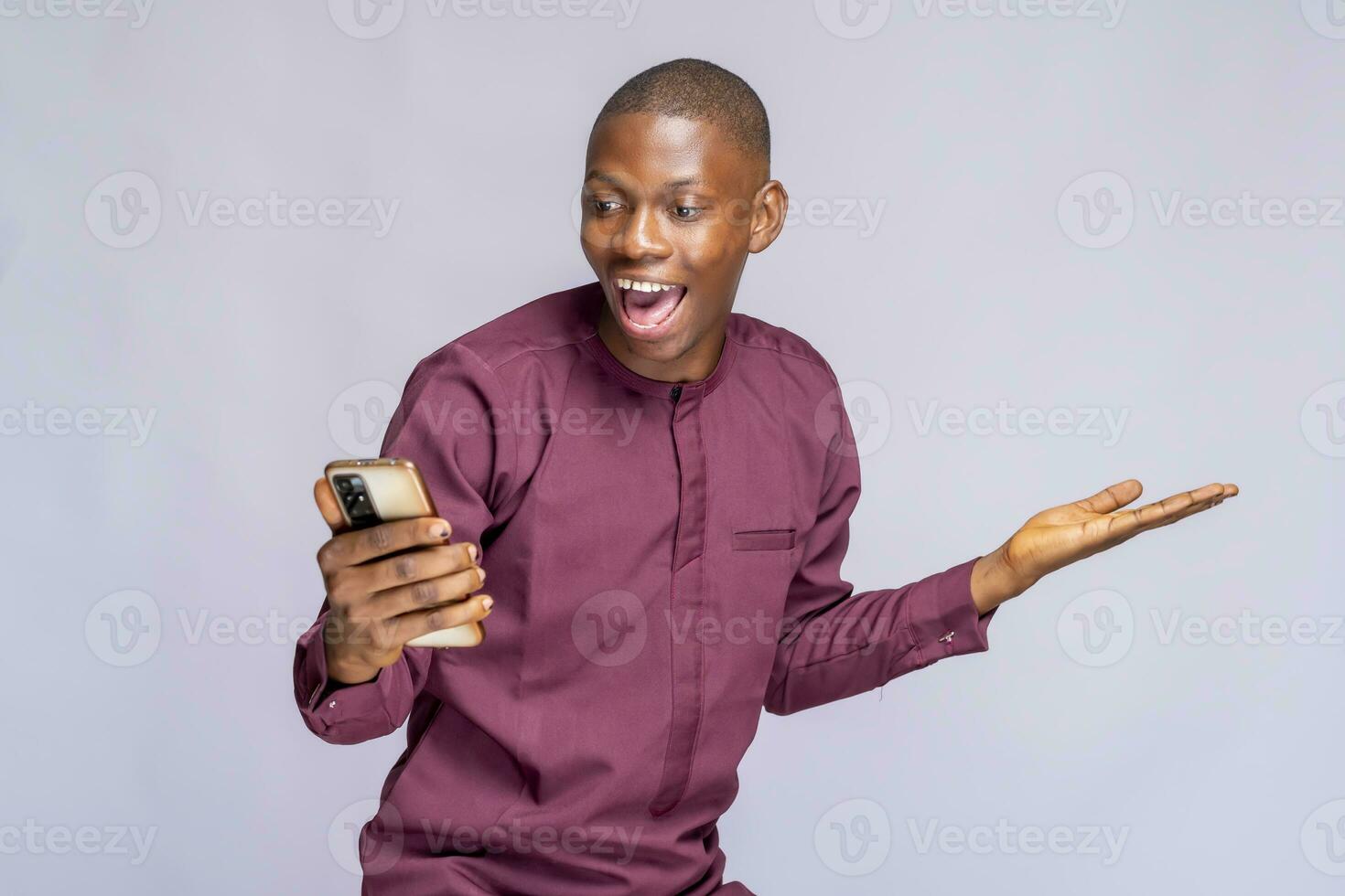 Super happy african guy in authentic costume using mobile phone celebrating success over white background, copy space photo