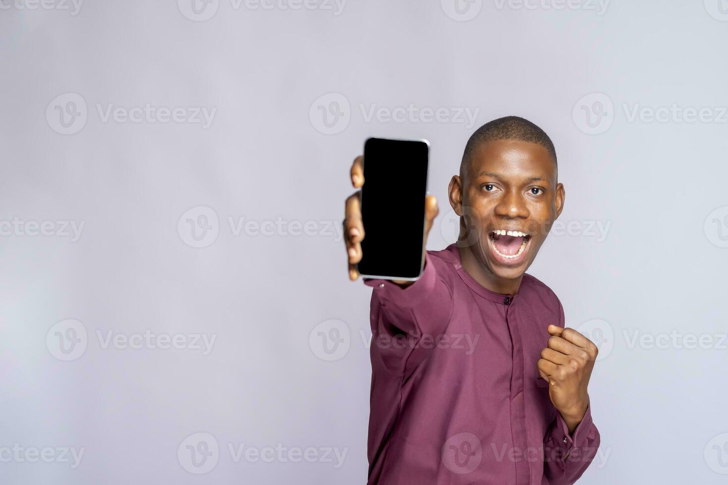 Smiling young african american man guy african clothing, posing isolated on white wall background. Hold mobile phone with blank empty screen People lifestyle concept. photo