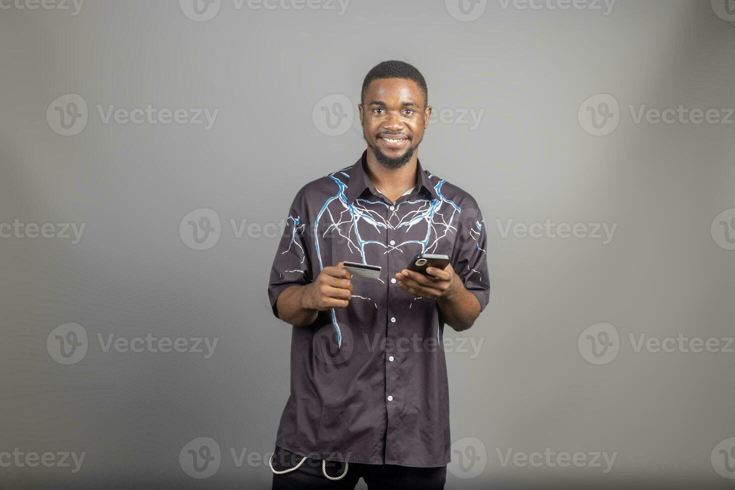 handsome young black man using his credit card and phone to shop online, banking online concepts photo