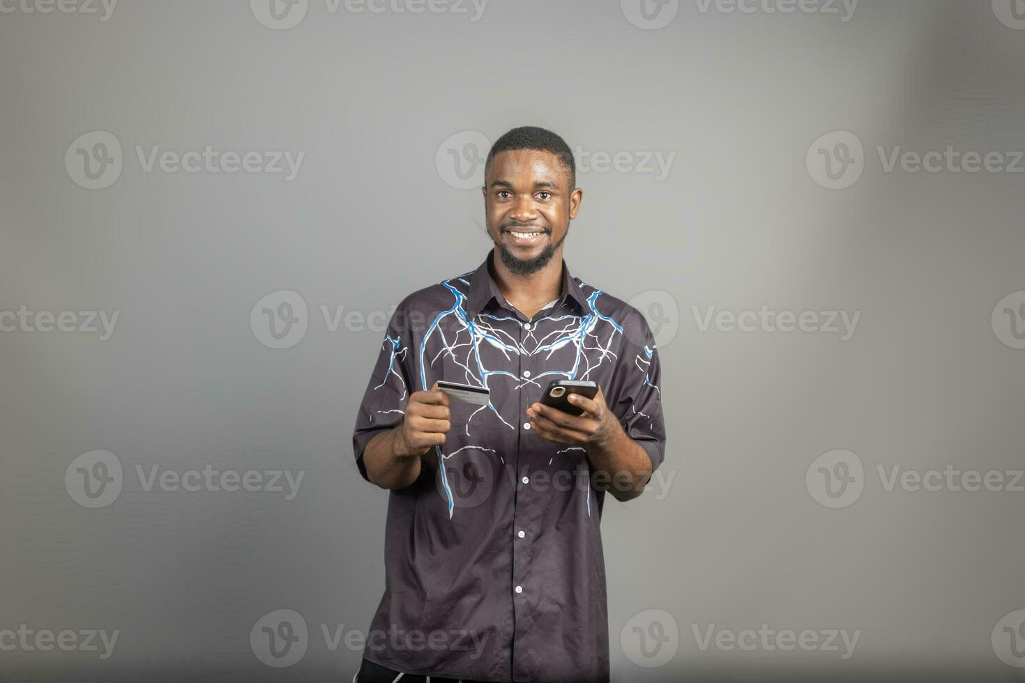 handsome young black man using his credit card and phone to shop online, banking online concepts photo