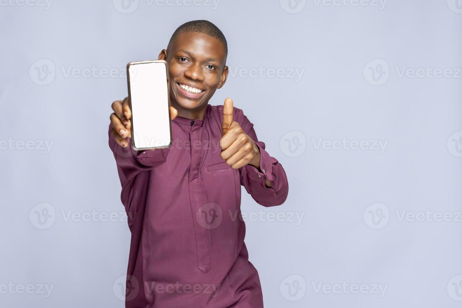 Portrait Young smiling happy balck african man 20s in hold in hand use mobile cell phone with blank screen workspace area show thump up gesture isolated on plain white background studio photo