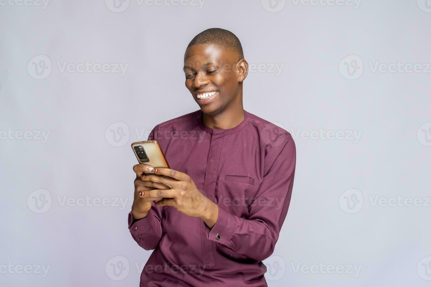 Portrait of cheerful African American student typing a message on smart phone, sharing success with his friends via social networks over white background photo
