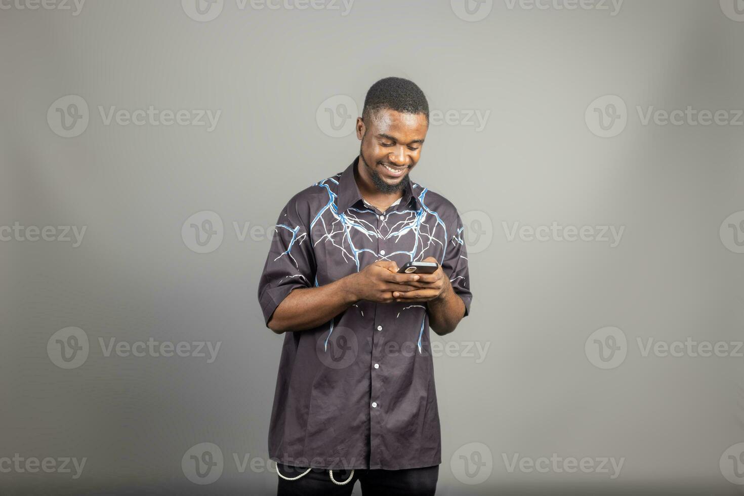 Attractive African American man texting on his phone isolated over grey photo