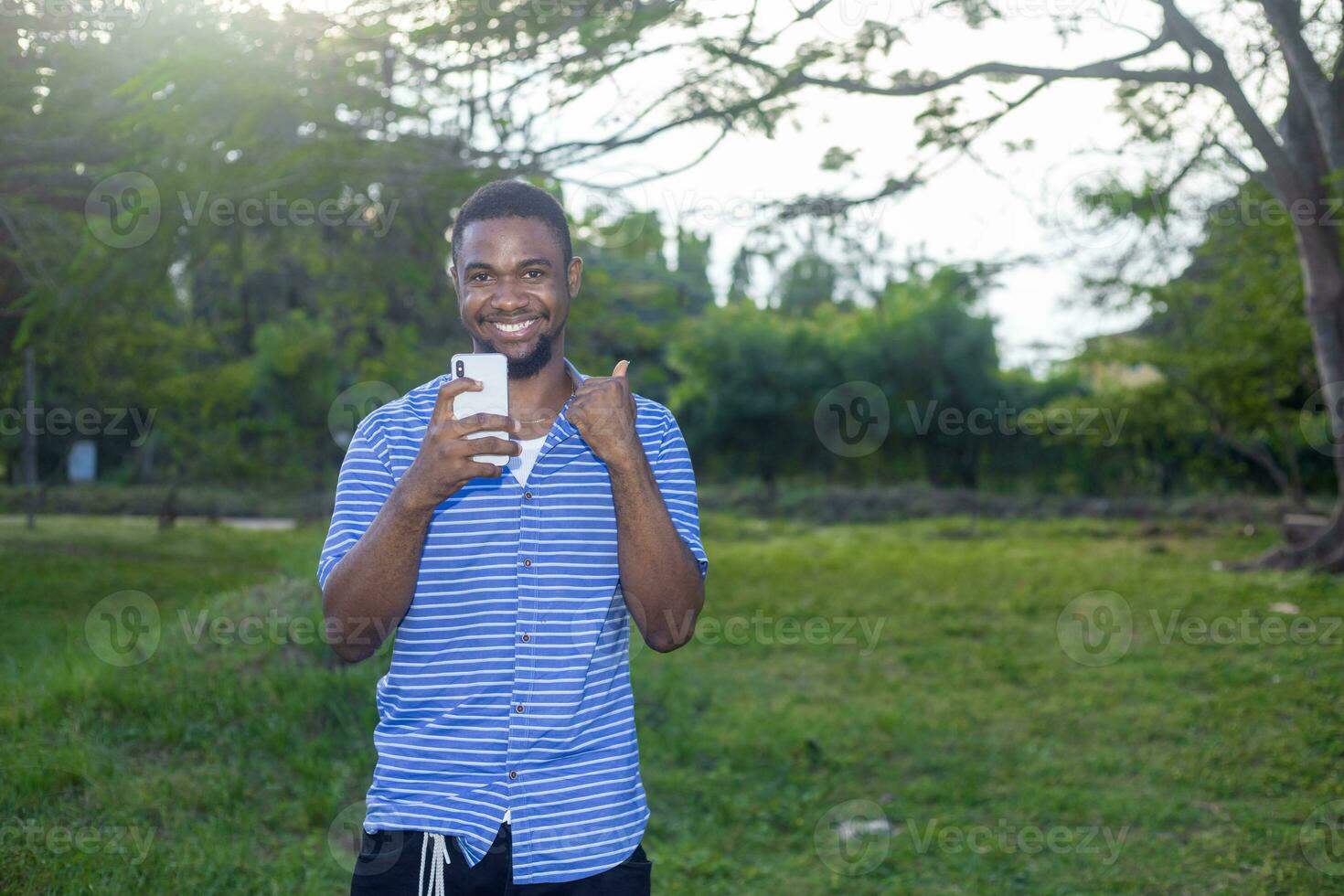 Smiling man in casual clothes use his mobile phone while standing photo