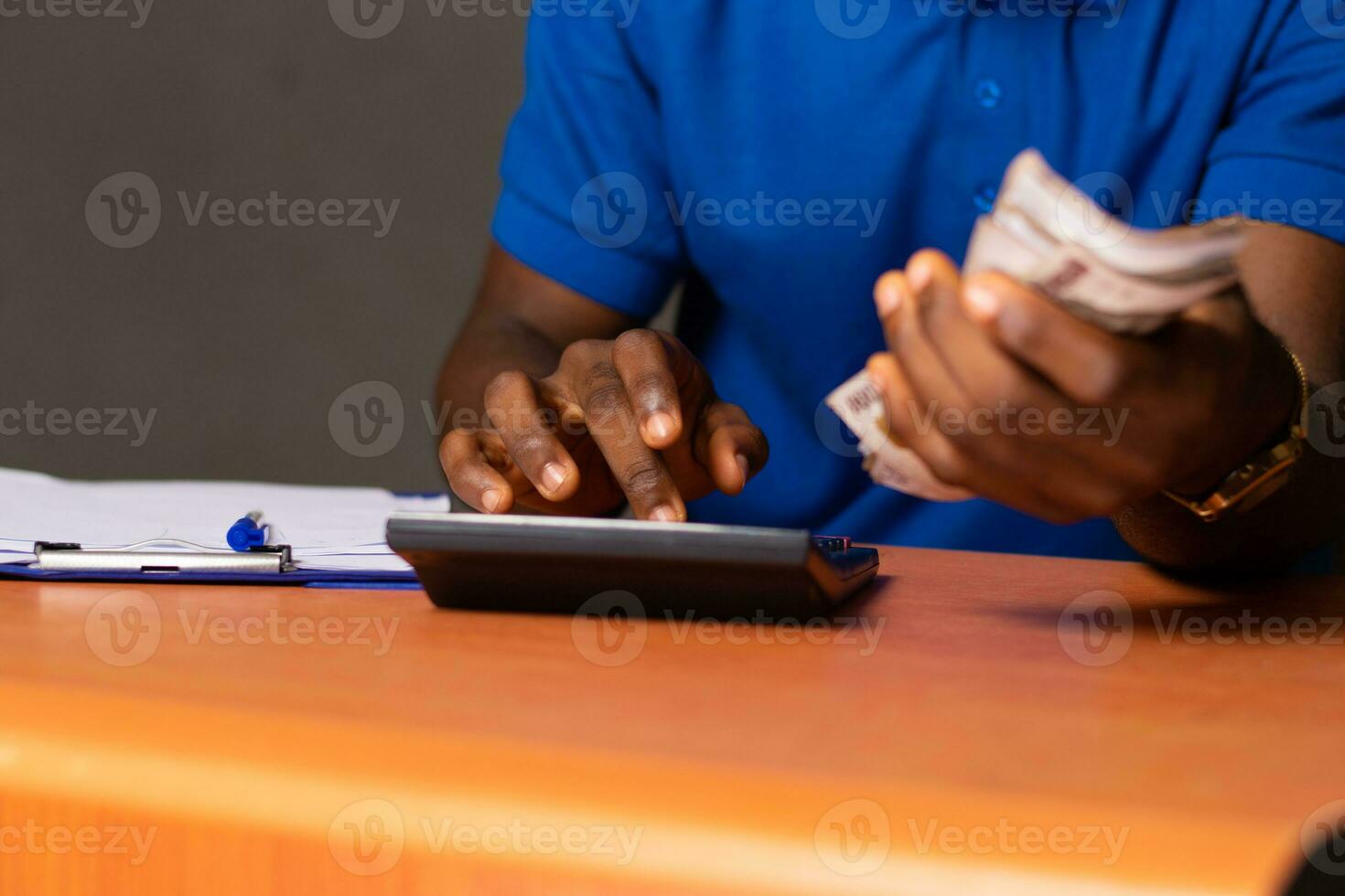 black person holding some money and doing some calculations with a calculator photo