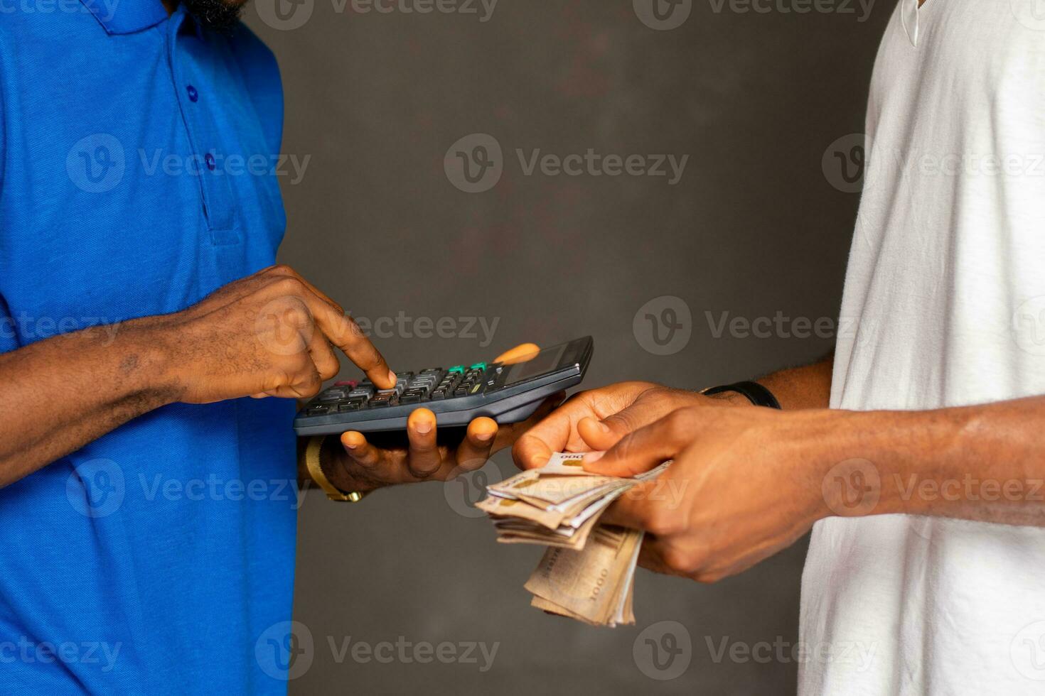someone counting some naira as another person uses a calculator photo