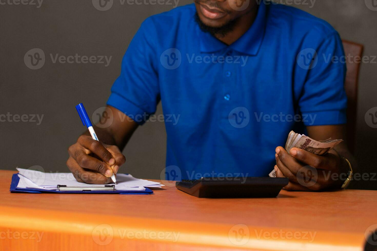 black young man doing some calculations, holding some money photo