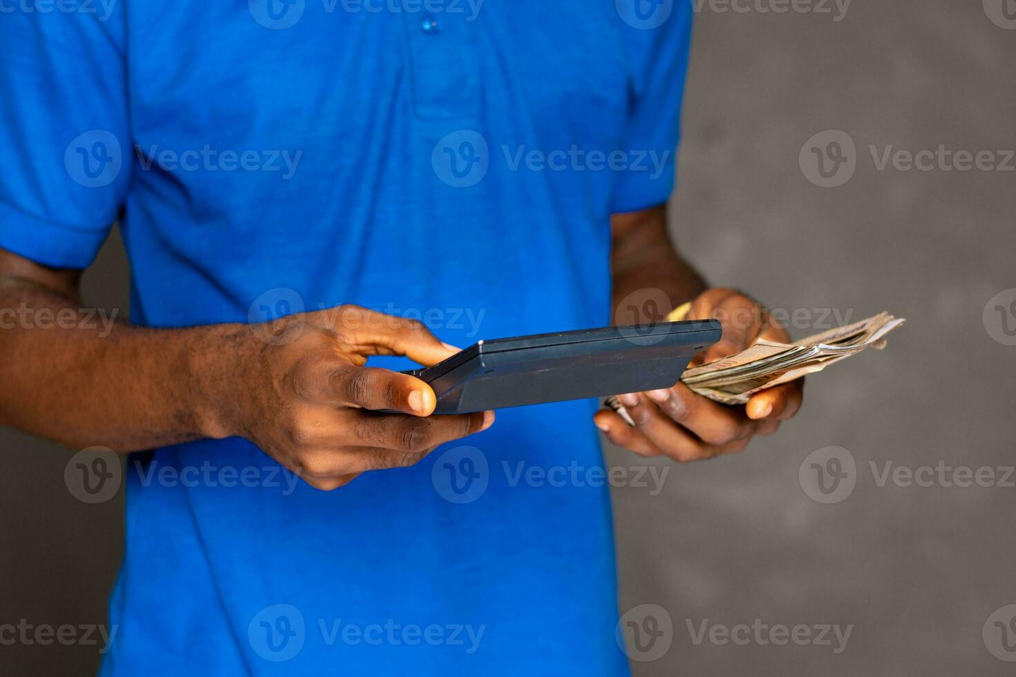 person using a calculator and holding some money photo