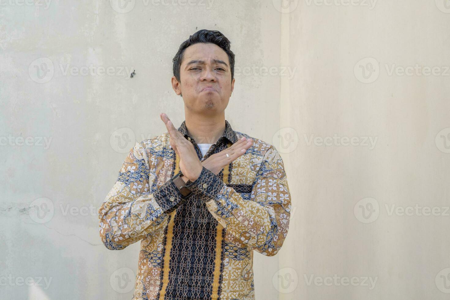 Young Indonesian wear batik traditional culture of Indonesia with rejected gesture. photo