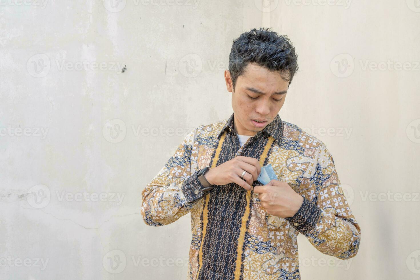 joven indonesio vestir batik tradicional cultura Indonesia cuando tomar dinero desde el bolsillo. foto