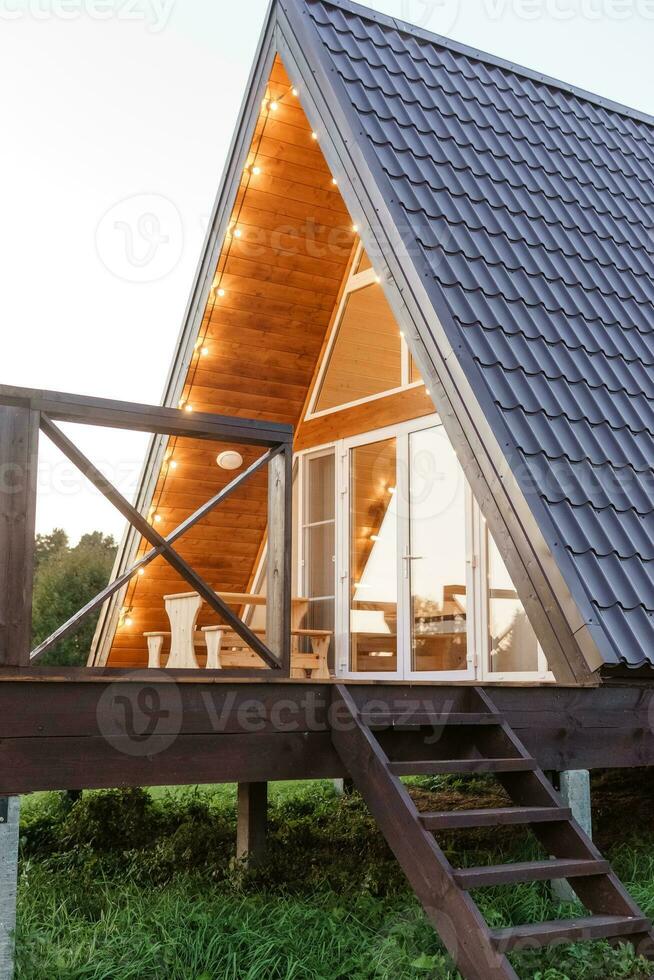 The concept of glamping and renting a chalet for weekend. Wooden house with a veranda in nature around coniferous trees photo