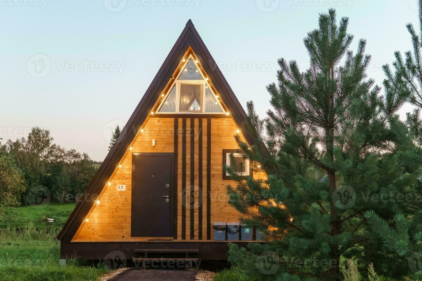 The concept of glamping and renting a chalet for weekend. Wooden house with a veranda in nature around coniferous trees photo