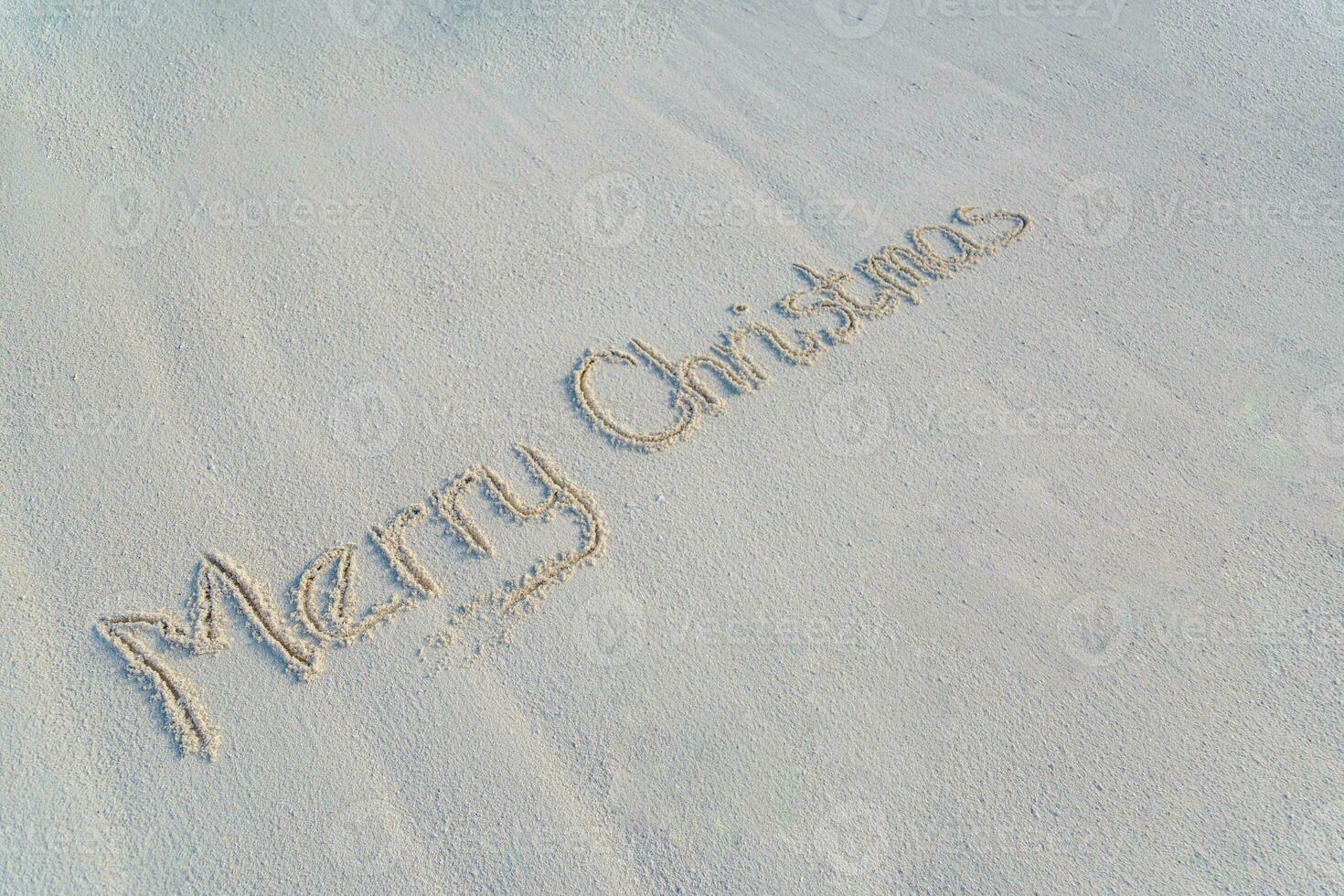 Merry Christmas beach text handwritten in sand on a beach background photo