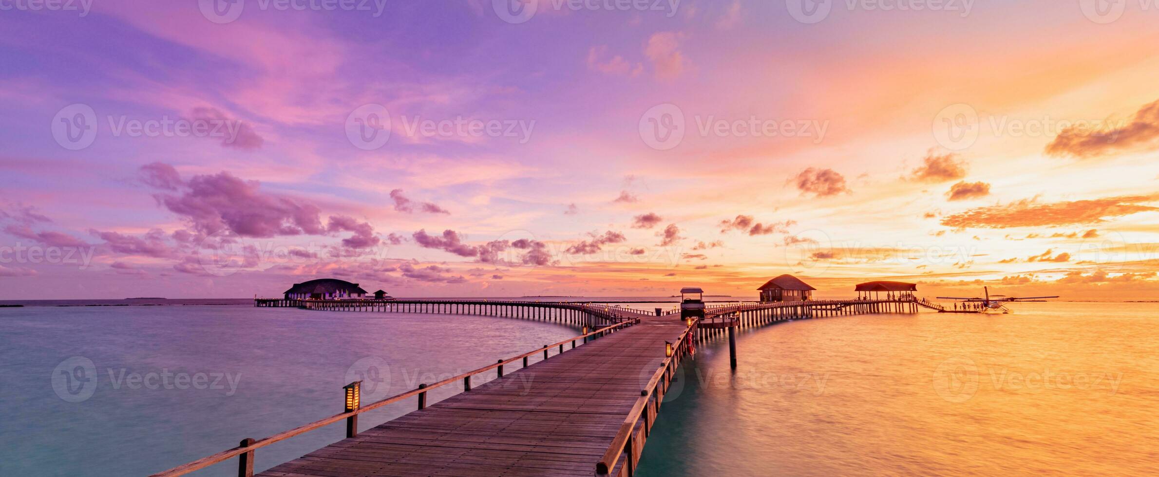 Amazing beach landscape. Beautiful Maldives sunset seascape view. Horizon colorful sea sky clouds, over water villa pier pathway. Tranquil island lagoon, tourism travel background. Exotic vacation photo