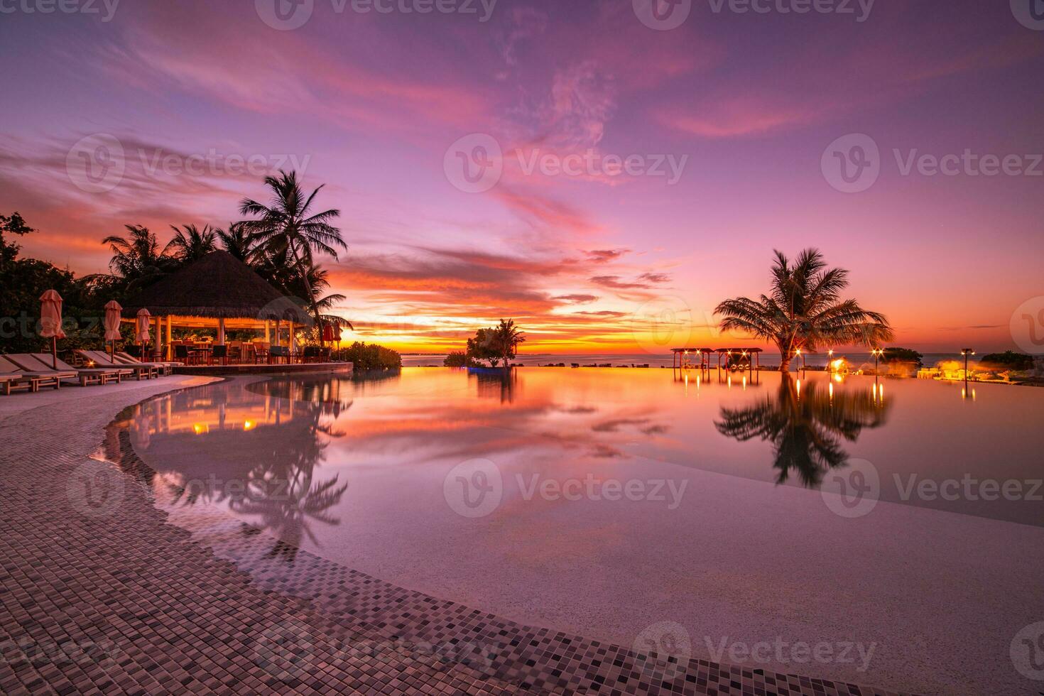 Amazing mood with poolside and palms next to beach and the ocean. Sunset sky and calm sea for luxury vacation tourism concept photo