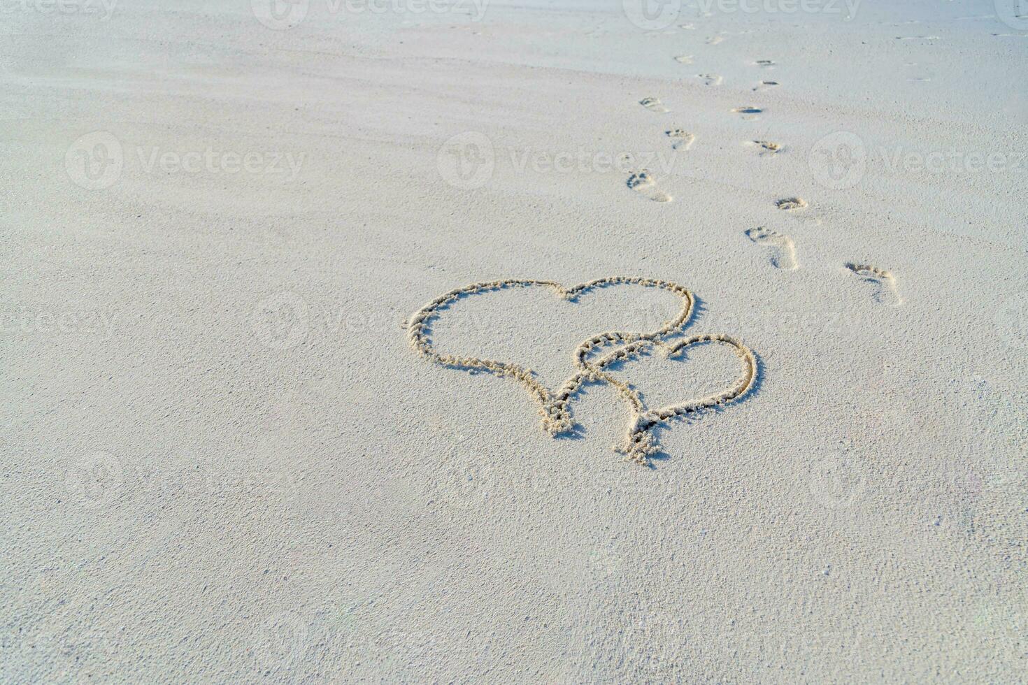 dos corazones en el playa, tropical Luna de miel o aniversario. dibujo en arena con pasos romántico viaje concepto foto