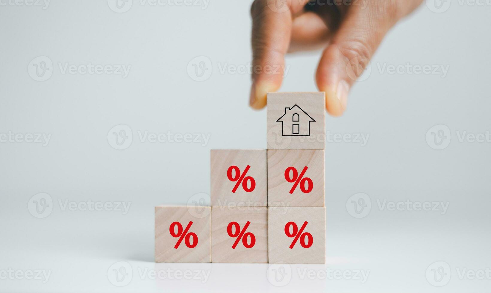 Hand holding house icon with percent sign from stack of blocks with percentage icon. House and property investment and asset management concept. Interest rates, loan mortgage, house tax. photo