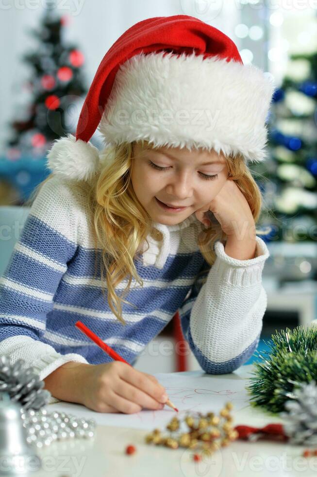 Happy girl in Santa hat sitting with Christmas present photo