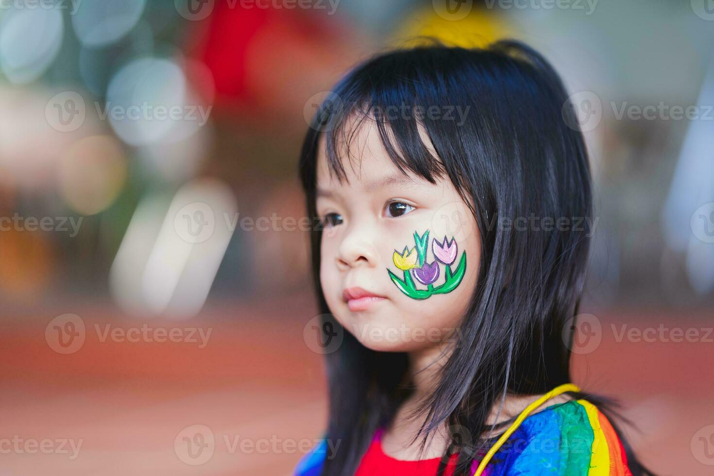 Cute kid girl cheeks are painted with flowers at Easter event. Empty space for entering text. photo