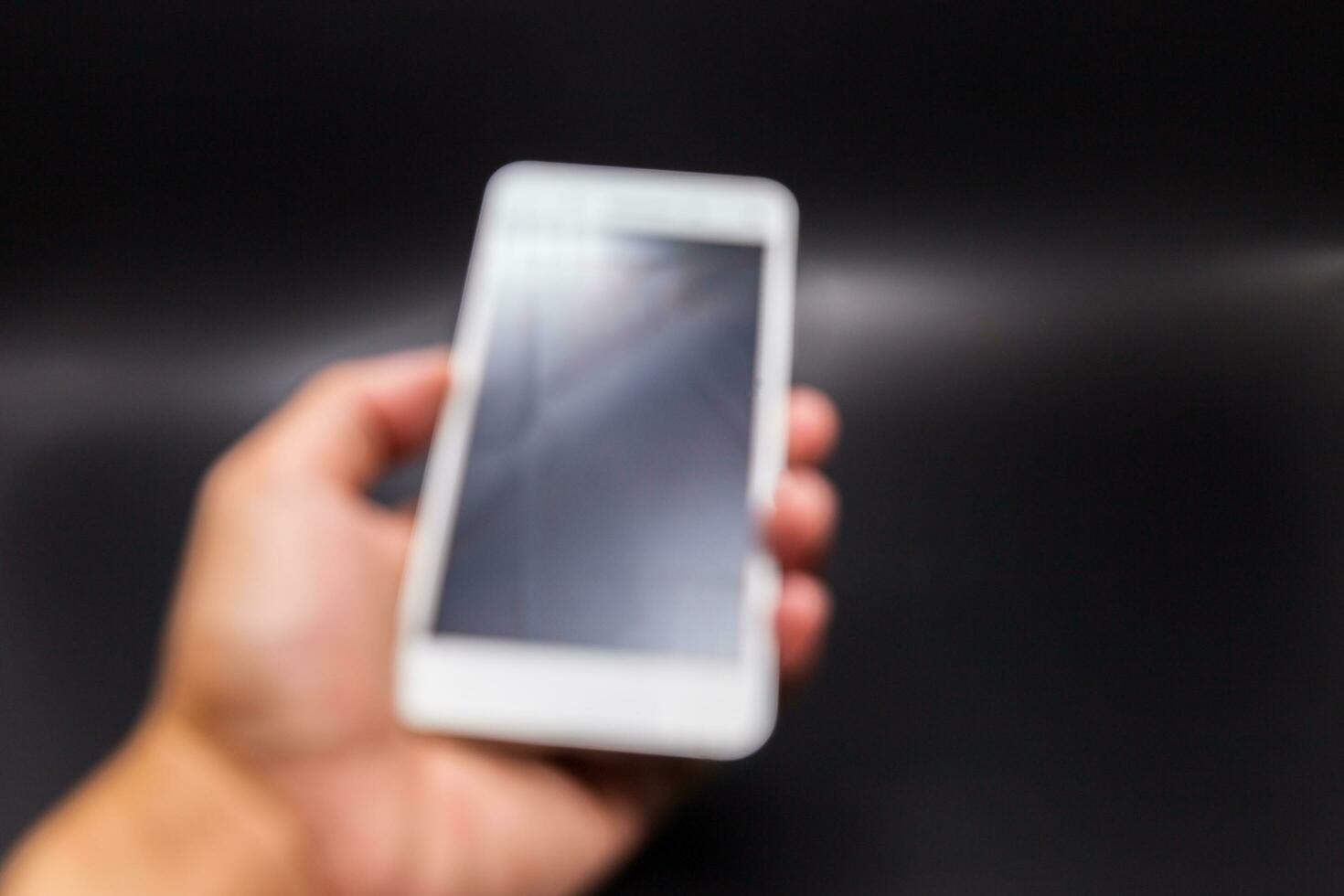 Hand holding mobile phone with black background photo