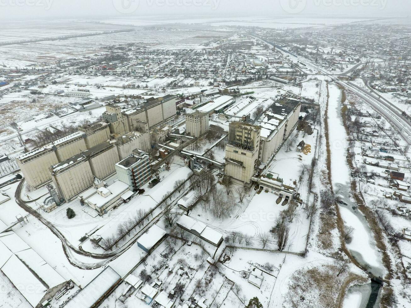 Sprinkled with snow grain elevator. Winter view of the old Soviet elevator. Winter view from the bird's eye view of the village. The streets are covered with snow photo