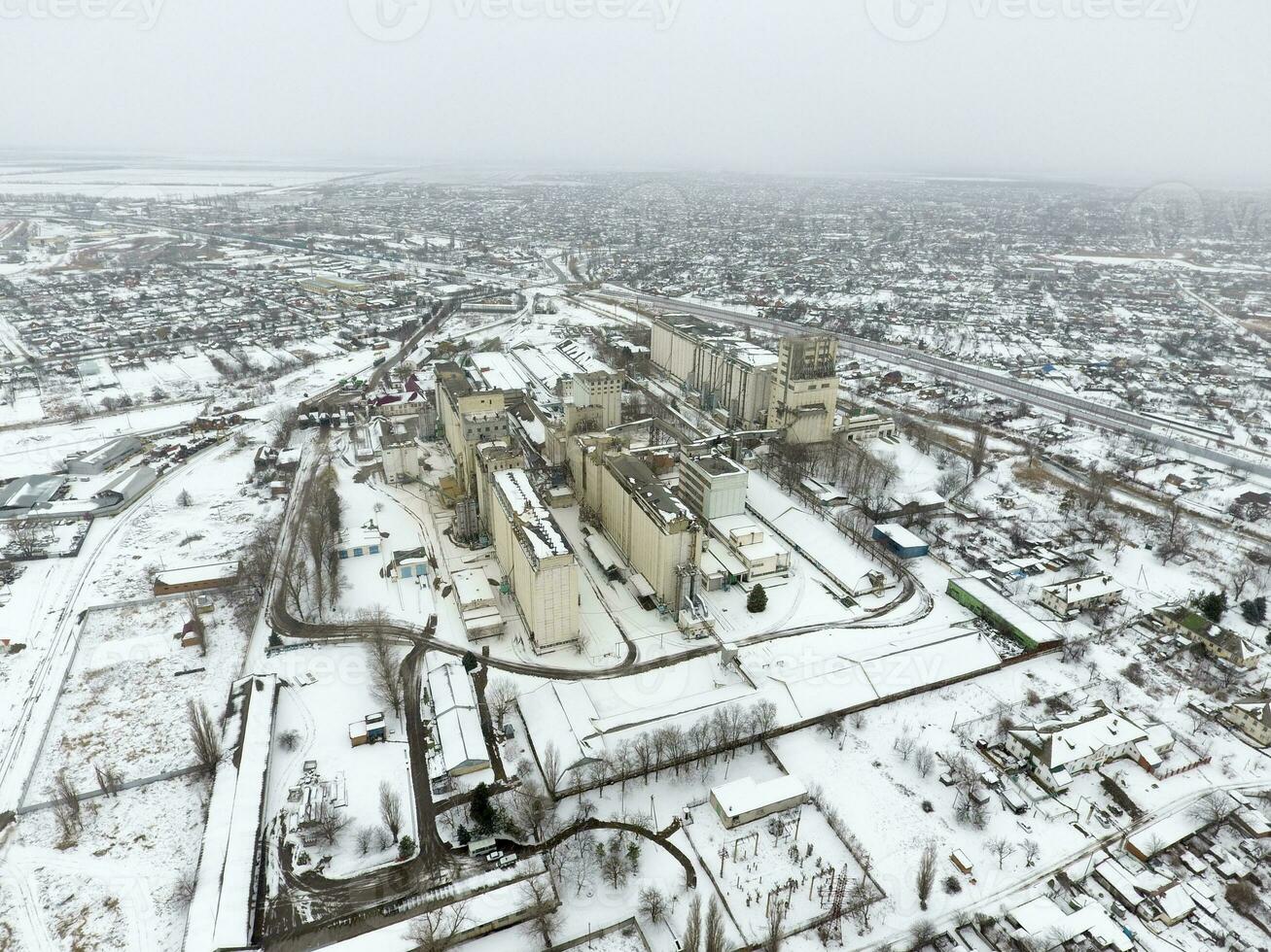 Sprinkled with snow grain elevator. Winter view of the old Soviet elevator. Winter view from the bird's eye view of the village. The streets are covered with snow photo